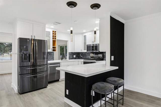 kitchen with white cabinets, light hardwood / wood-style flooring, tasteful backsplash, kitchen peninsula, and stainless steel appliances