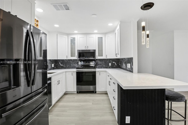 kitchen with a breakfast bar area, white cabinets, hanging light fixtures, and appliances with stainless steel finishes