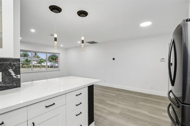 kitchen with pendant lighting, white cabinets, backsplash, and stainless steel refrigerator