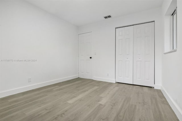 unfurnished bedroom with a closet and light hardwood / wood-style flooring