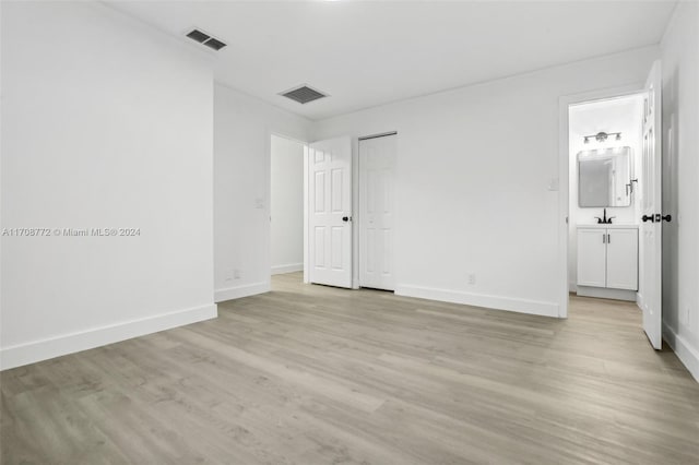 unfurnished bedroom with ensuite bath and light hardwood / wood-style floors