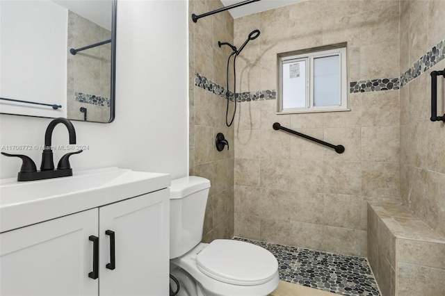 bathroom featuring a tile shower, vanity, and toilet