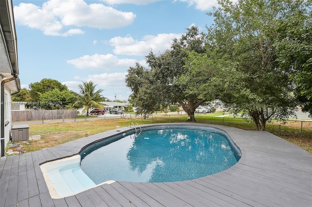 view of swimming pool featuring a lawn and a wooden deck