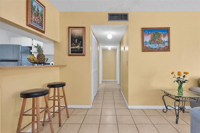 hall featuring light tile patterned floors and a textured ceiling