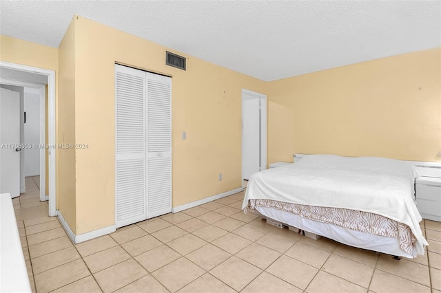 bedroom featuring light tile patterned floors, a textured ceiling, and a closet