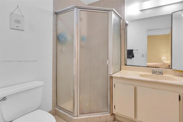 bathroom featuring vanity, toilet, and a shower with shower door