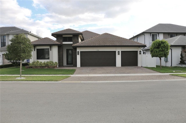 prairie-style home featuring a garage and a front lawn