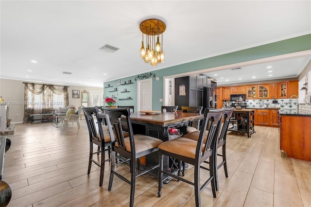 dining space featuring ornamental molding, visible vents, and light wood finished floors