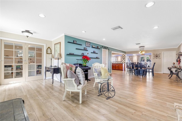 living area with light wood-style flooring, ornamental molding, and french doors