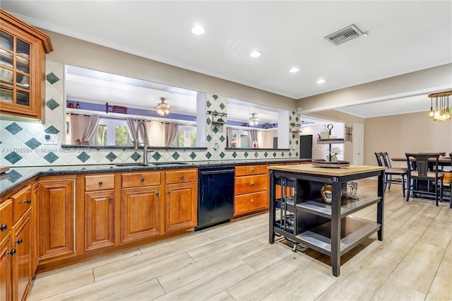 kitchen featuring visible vents, a sink, glass insert cabinets, and brown cabinets