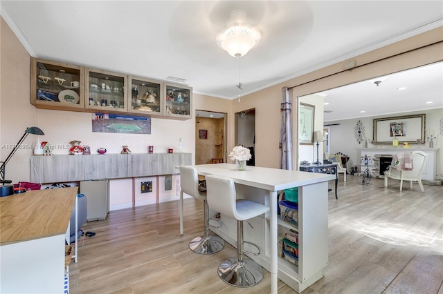 kitchen with ornamental molding, light wood-style floors, light countertops, and a fireplace