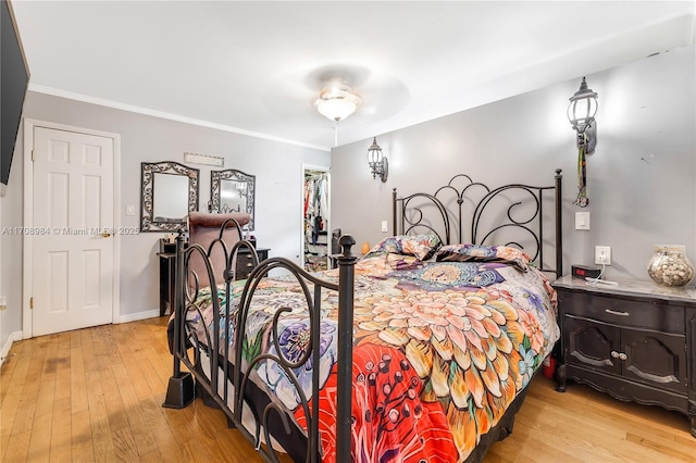 bedroom featuring light wood finished floors, baseboards, and crown molding