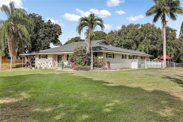 view of front of house featuring fence, a front lawn, and stucco siding