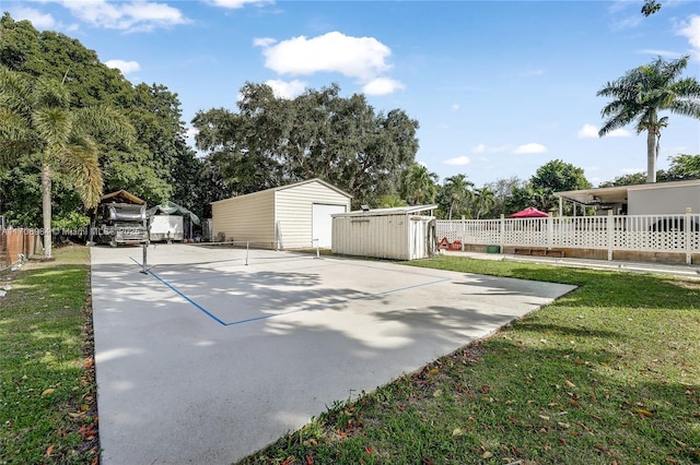 exterior space with an outbuilding, basketball court, a storage shed, a detached garage, and fence