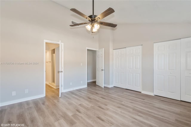 unfurnished bedroom with ceiling fan, high vaulted ceiling, light hardwood / wood-style floors, and two closets