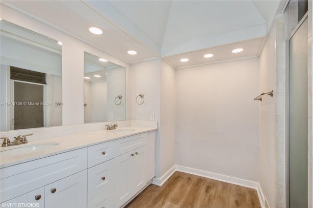 bathroom with wood-type flooring, vanity, vaulted ceiling, and walk in shower