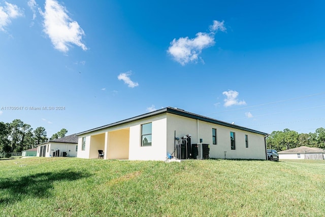 back of house with a lawn and central AC unit