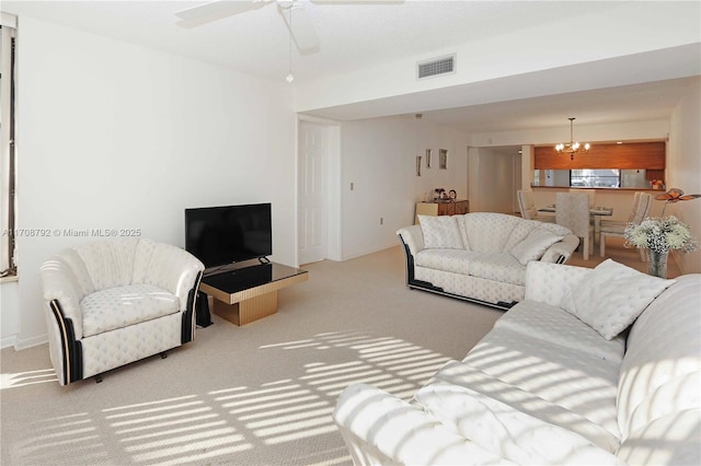 carpeted living room featuring ceiling fan with notable chandelier