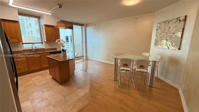 kitchen with stainless steel refrigerator, sink, light hardwood / wood-style flooring, pendant lighting, and a kitchen island