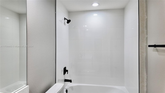 bathroom featuring tiled shower / bath combo and toilet