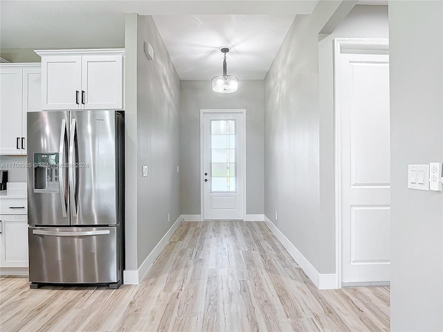 kitchen with white cabinetry, stainless steel fridge, hanging light fixtures, and light hardwood / wood-style floors