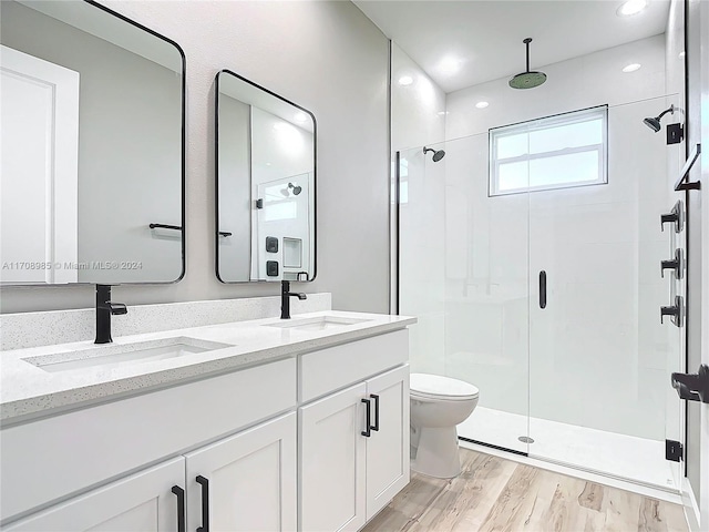 bathroom featuring wood-type flooring, vanity, toilet, and an enclosed shower