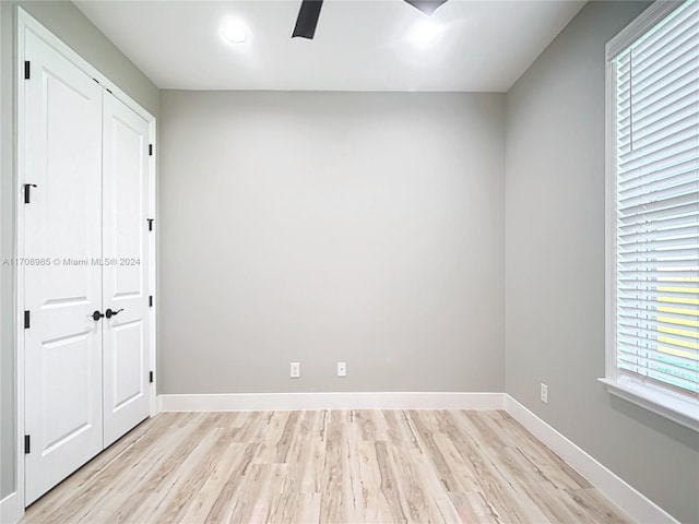 unfurnished bedroom featuring a closet, light hardwood / wood-style flooring, multiple windows, and ceiling fan