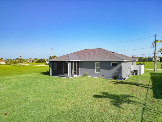 back of property featuring a sunroom, central AC unit, and a lawn