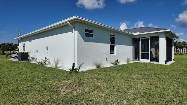 rear view of property featuring a lawn, a sunroom, and central air condition unit