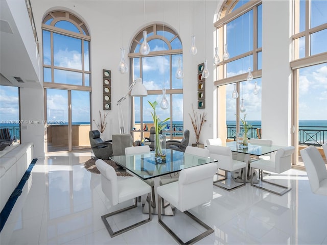 dining area featuring a water view and a high ceiling