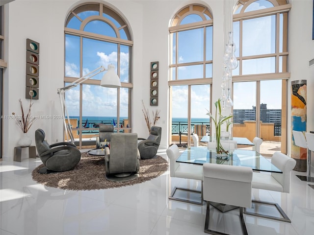 living room featuring tile patterned flooring, a towering ceiling, and a water view