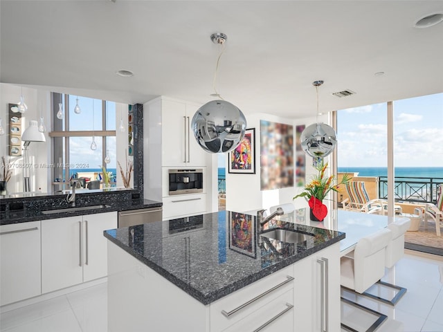 kitchen with white cabinets, a water view, sink, and dark stone counters