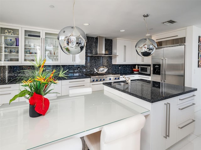 kitchen with wall chimney exhaust hood, white cabinetry, hanging light fixtures, and appliances with stainless steel finishes