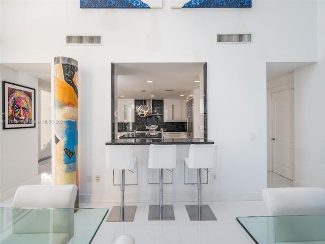 interior space with kitchen peninsula, backsplash, a breakfast bar, stainless steel built in fridge, and white cabinetry