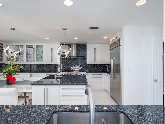 kitchen featuring white cabinetry, sink, wall chimney exhaust hood, built in refrigerator, and pendant lighting