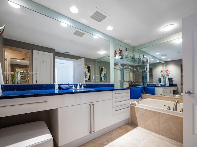 bathroom featuring tile patterned flooring, vanity, and tiled bath