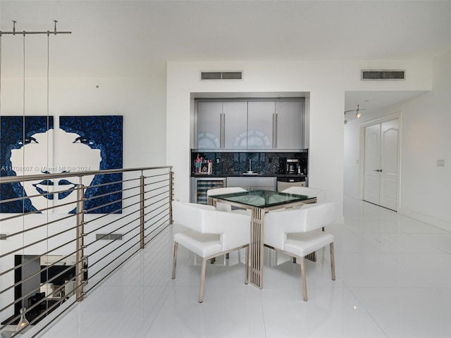 kitchen featuring backsplash, dishwasher, light tile patterned floors, and beverage cooler