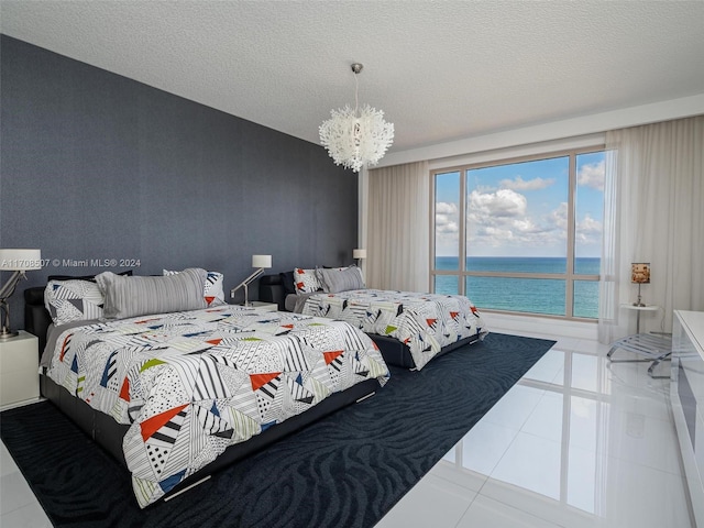 tiled bedroom featuring a water view, a chandelier, and a textured ceiling