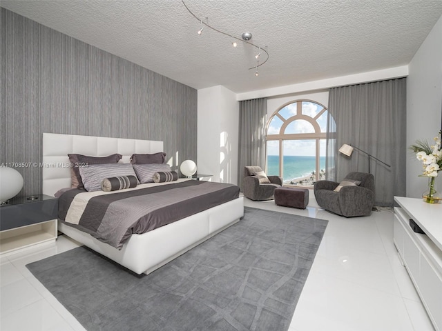 tiled bedroom with a water view and a textured ceiling