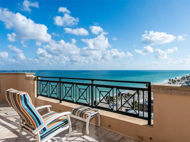 balcony with a water view and a view of the beach