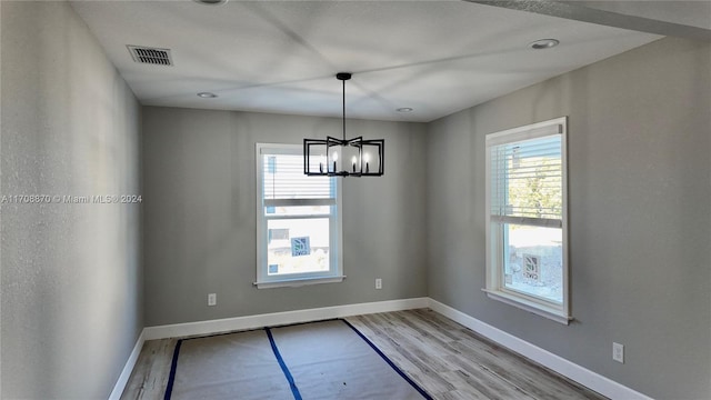 unfurnished room with light hardwood / wood-style floors and an inviting chandelier