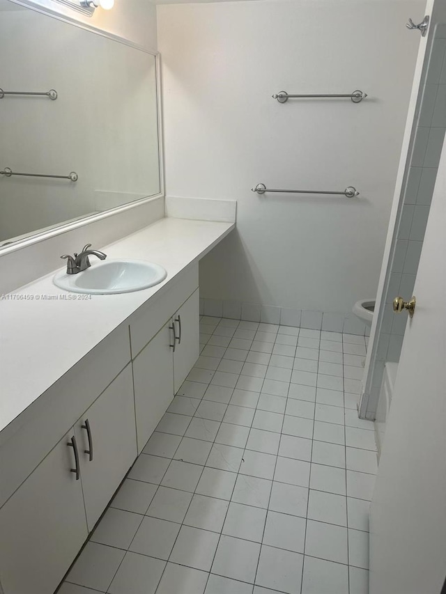 bathroom featuring tile patterned flooring, a bath, vanity, and toilet