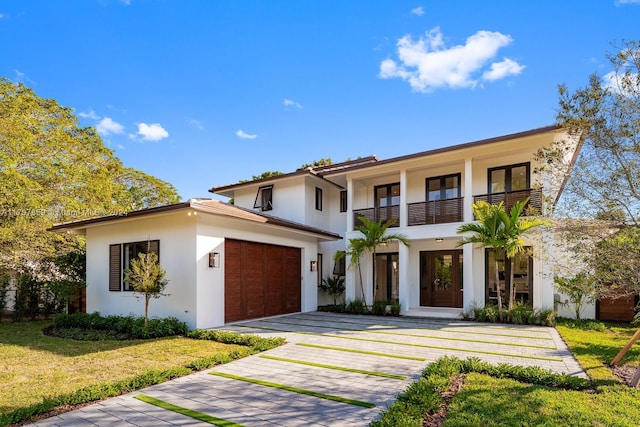 view of front of house featuring a balcony, a front yard, and a garage