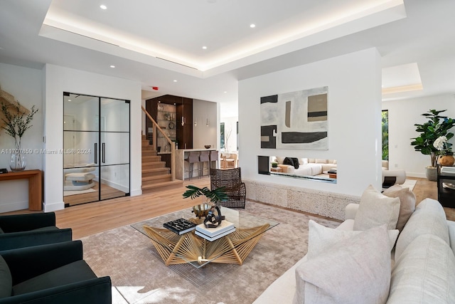 living room with light hardwood / wood-style flooring and a tray ceiling