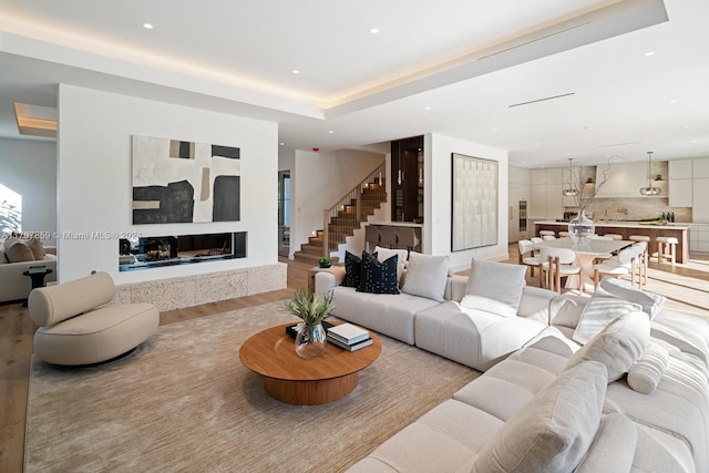 living room featuring a tray ceiling and light wood-type flooring