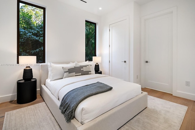 bedroom with light hardwood / wood-style flooring and multiple windows