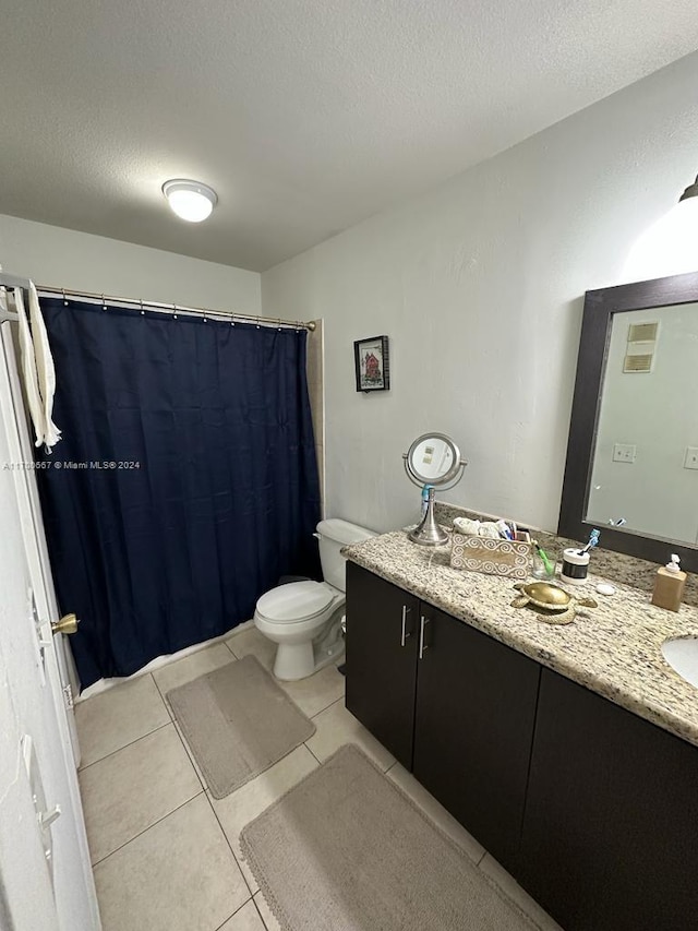 bathroom with tile patterned floors, vanity, a textured ceiling, and toilet