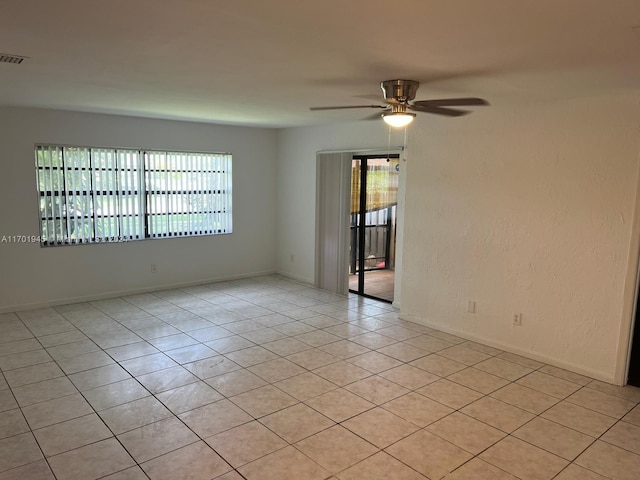 unfurnished room featuring a wealth of natural light, light tile patterned flooring, and ceiling fan