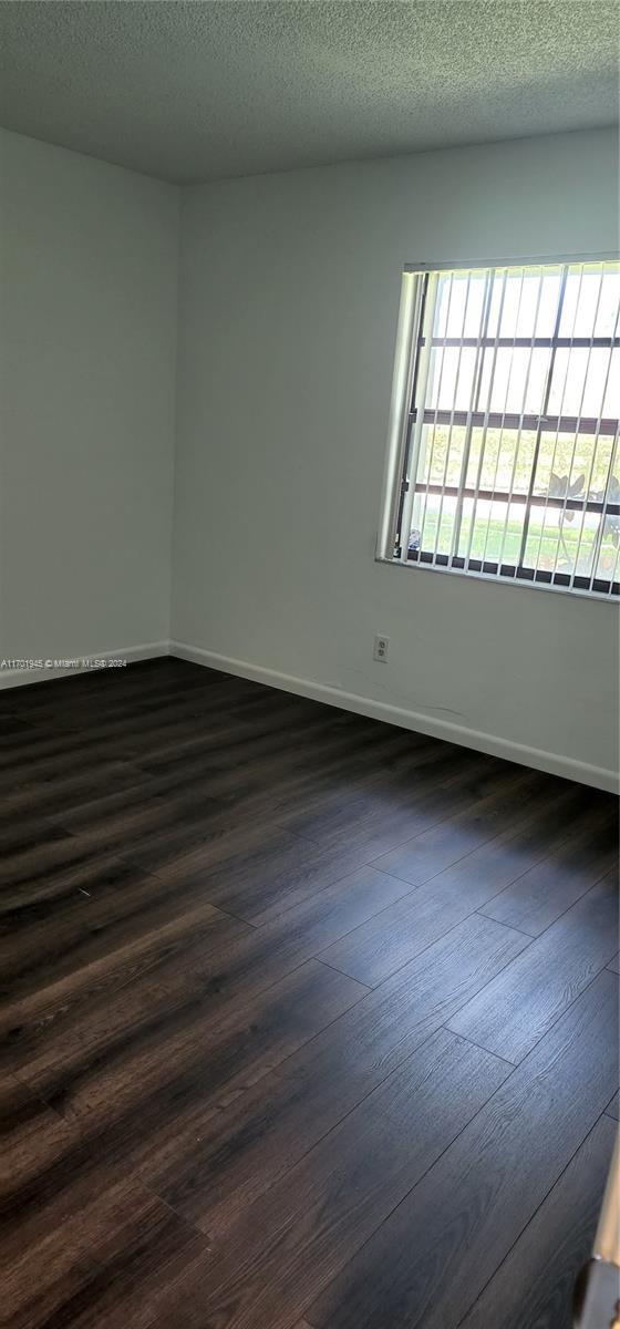 spare room featuring a textured ceiling and dark hardwood / wood-style floors