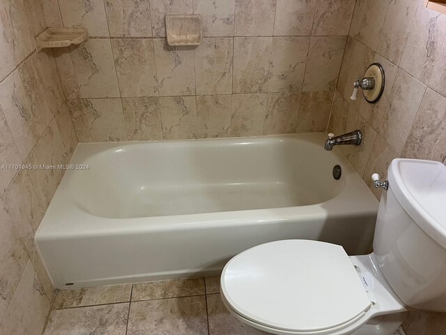 bathroom with tile patterned flooring, toilet, and tile walls